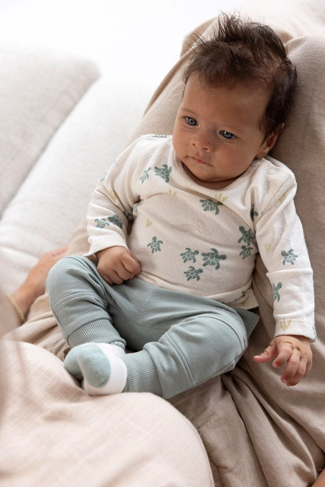 Baby met een Feetje Broek -Turtelly Cool aan